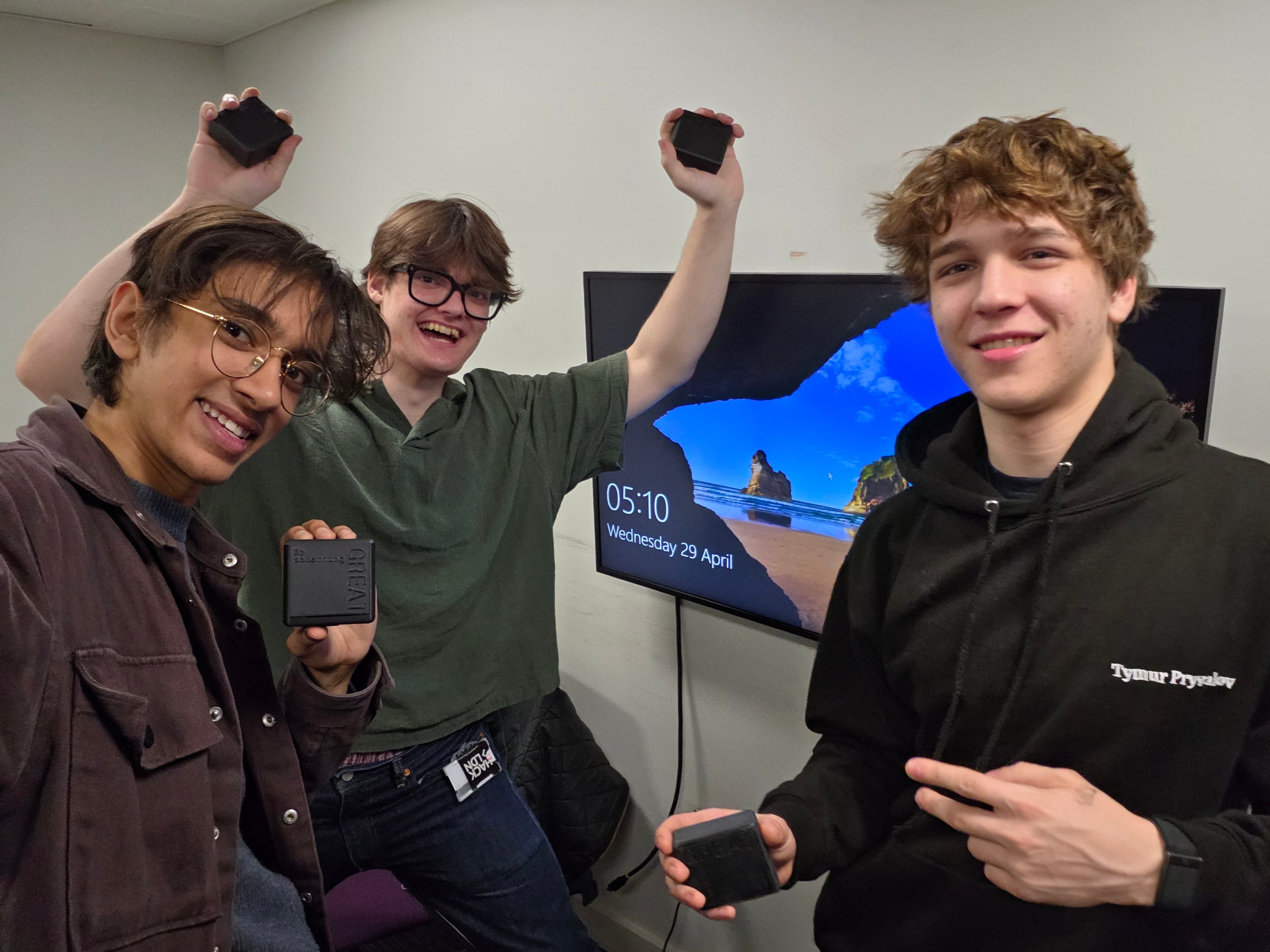 The three ClearZone founders deep in a late-night YC application push, each holding a production carbon fibre case